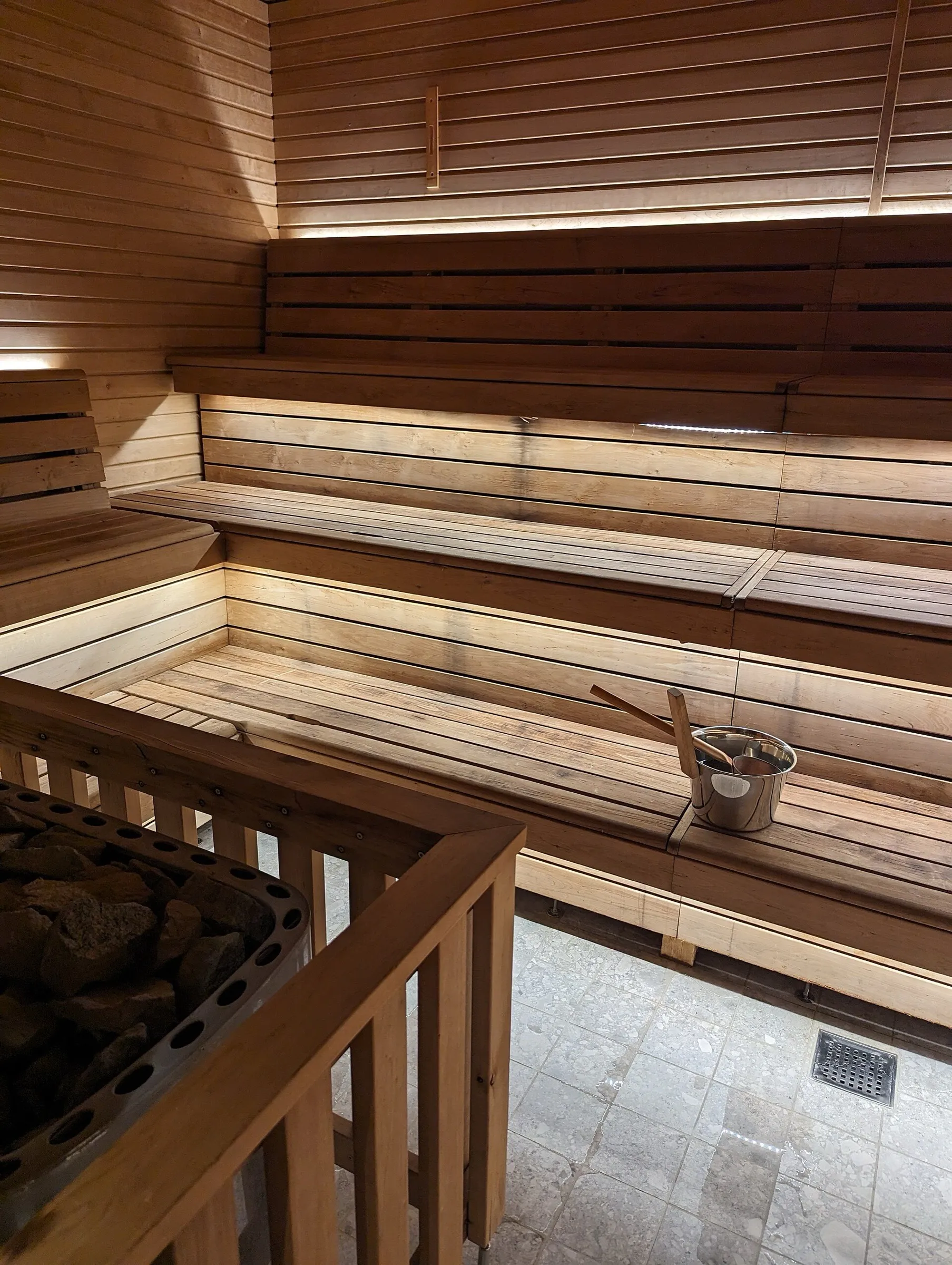 Bancos de madera de una sauna con balde y cucharón
